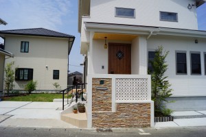 割肌の自然石の壁と白のスクリーンブロックで印象的な門周り