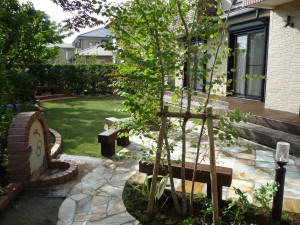 石貼りのテラスに枕木のベンチ、大きな木の木陰が快適空間